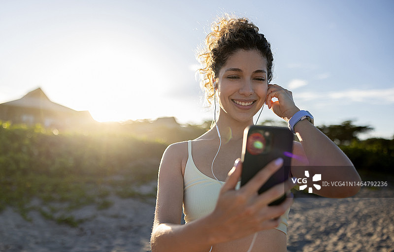 健康的女性在户外锻炼，用手机听音乐图片素材
