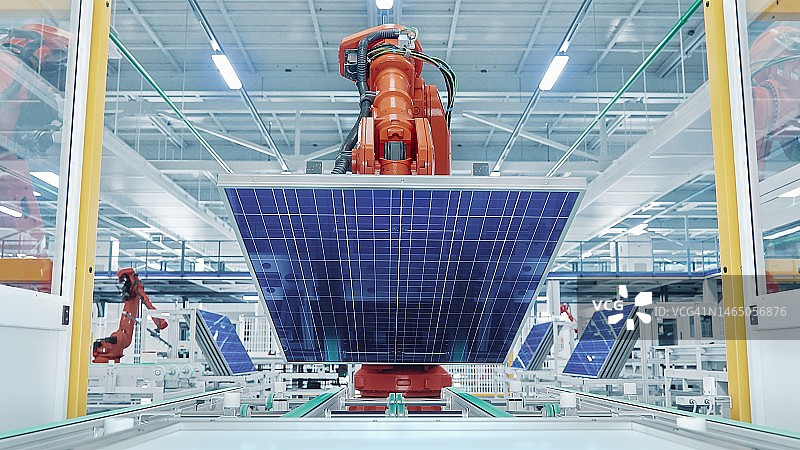 橙色工业机器人手臂抓取和移动输送机上的太阳能电池板。自动化制造设备。现代光明工厂生产线。图片素材