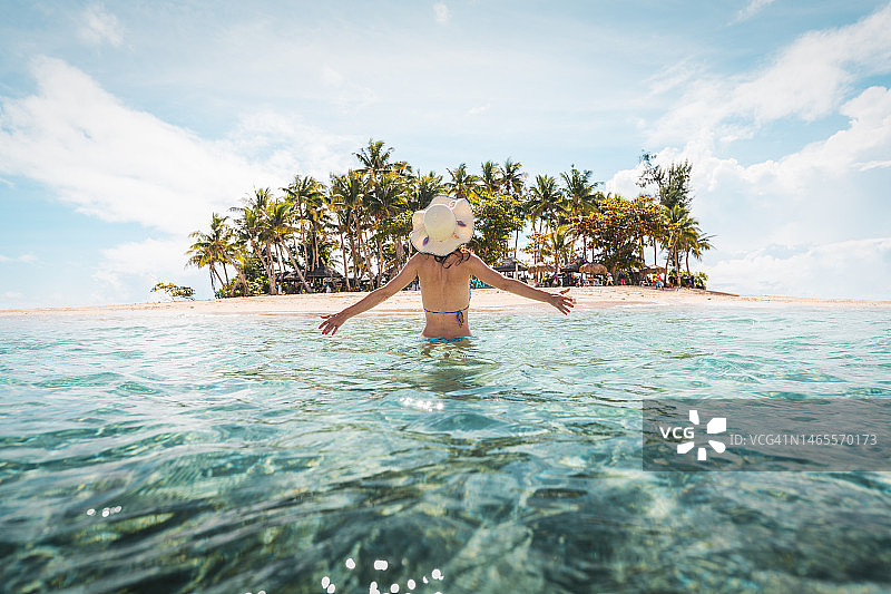 一名女子正在接近一个田园诗般的热带岛屿图片素材