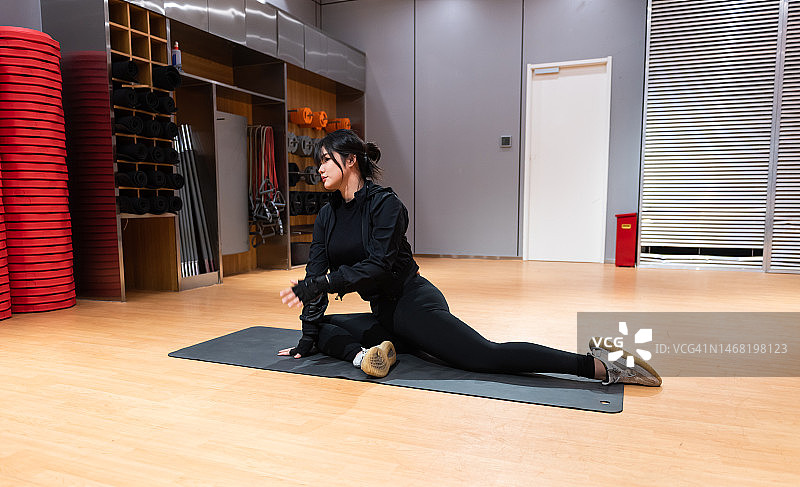 年轻女子穿着运动服坐在瑜伽垫上。积极的生活方式和健康图片素材