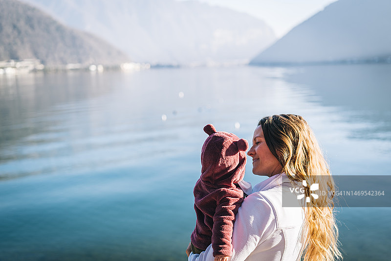 在湖岸，母亲抱着襁褓中的女儿图片素材