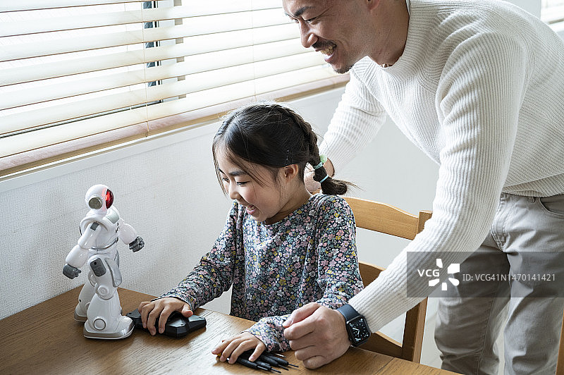 一个小女孩和爸爸一起做玩具机器人图片素材