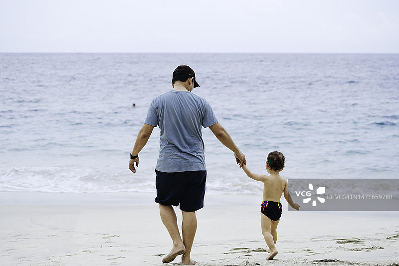 亚洲男人在沙滩上教他的孩子走路图片素材