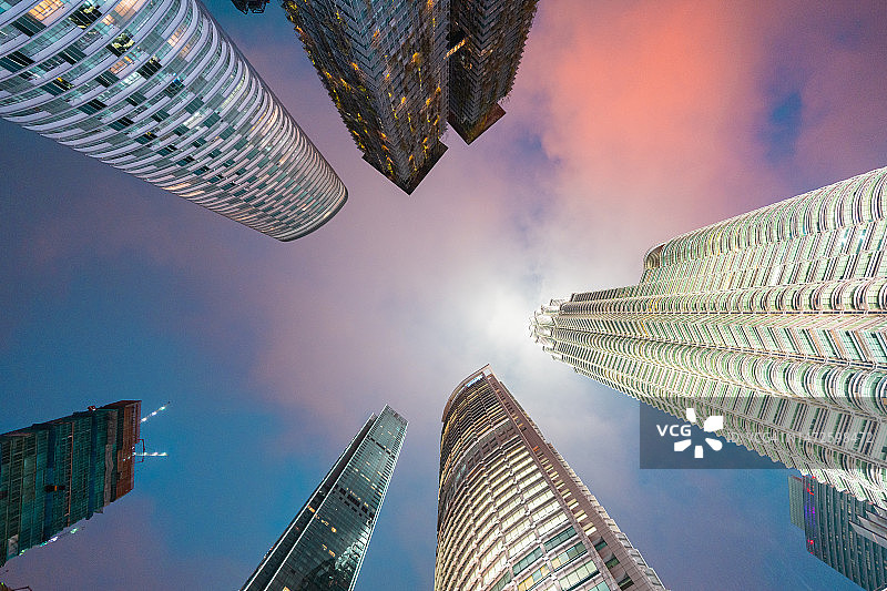 在马来西亚首都吉隆坡的暮色中，现代未来主义摩天大楼的低角度视图。图片素材