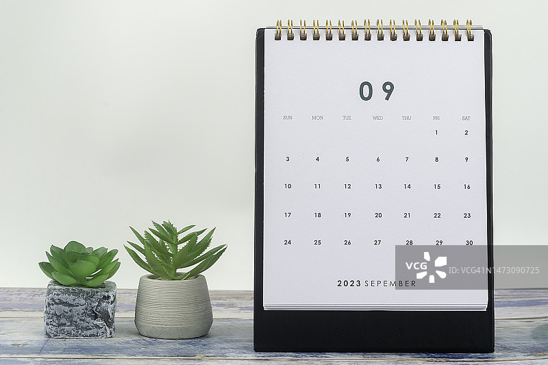日历桌2023:9月是组织者计划和截止日期的月份，以浅灰黄色背景为背景的室内植物。图片素材