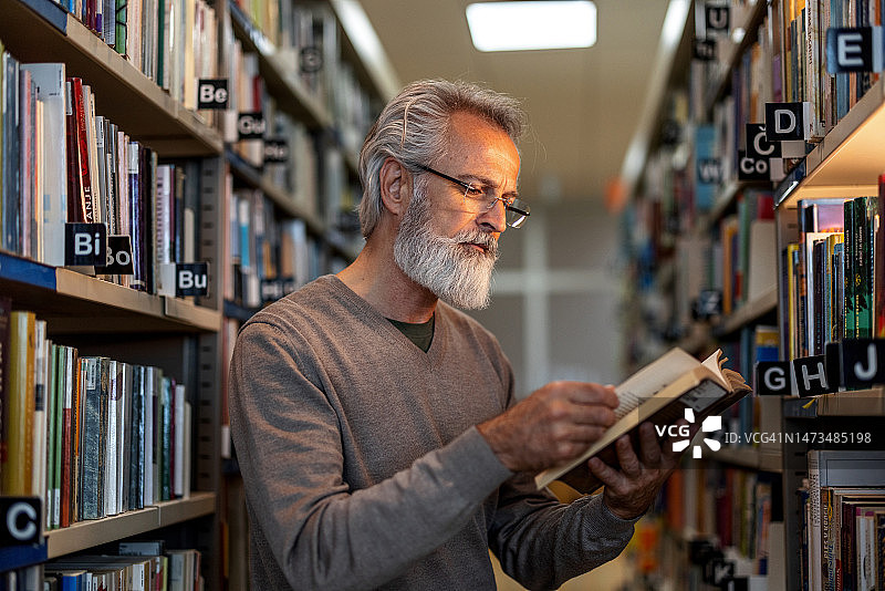 白人退休男子在市图书馆读书图片素材