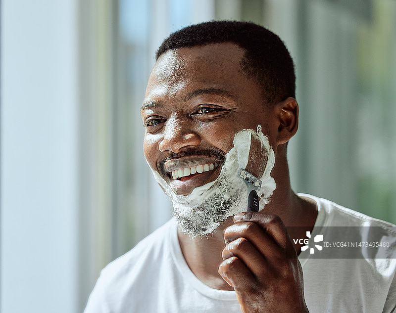 面部，剃须和剃须刀与一个黑人男子在他的家的浴室镜子美容或护肤。早上和一个英俊的男人一起剃须，刮胡子和刀片，为他的脱毛例行公事图片素材