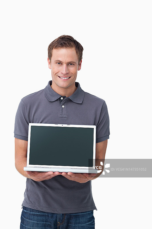 微笑的年轻人显示屏幕上的他的笔记本图片素材