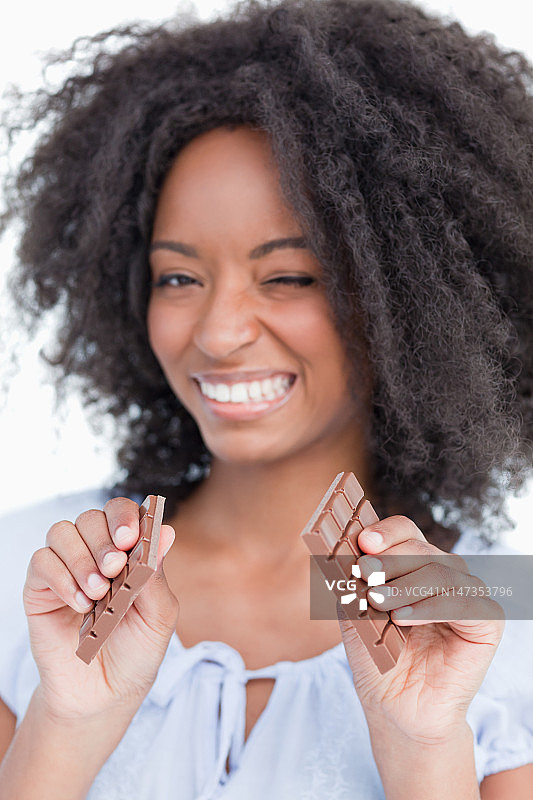 年轻女子把一块美味的巧克力掰成两半图片素材