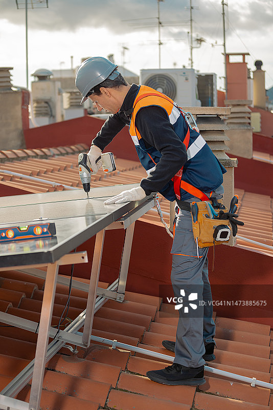 在屋顶安装太阳能电池板的专业工程师图片素材