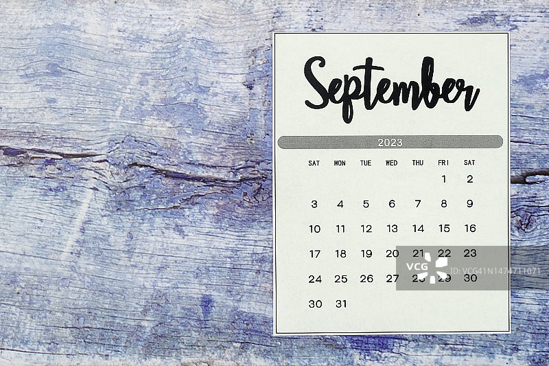 日历桌2023:9月是组织者计划和最后期限的月份，蓝色木制背景。图片素材