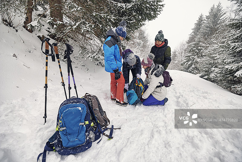 在一个大雪纷飞的冬日，一家人正在山林里搭帐篷。图片素材