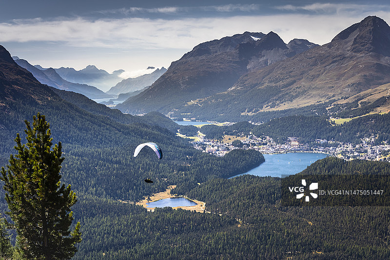 在瑞士阿尔卑斯山脉格劳宾登恩加丁山谷的穆奥塔斯·穆拉格尔乘坐滑翔伞飞越圣莫里茨湖图片素材