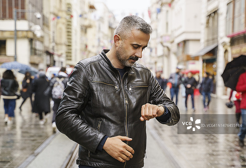 一个中年男子站在伊斯坦布尔的Istiklal大街上看时间图片素材