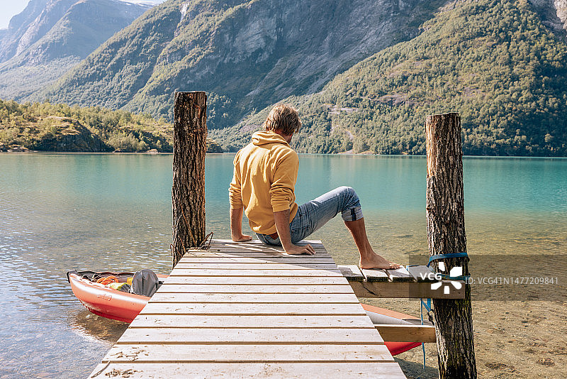 一名男子来到美丽的湖上的木码头，他准备了独木舟图片素材