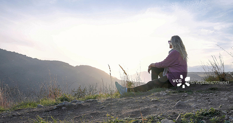 成熟的女性徒步旅行者在丘陵环境中放松图片素材