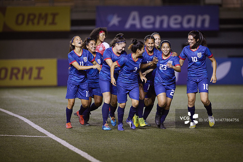 女子足球队的队员们在庆祝进球时一起奔跑图片素材