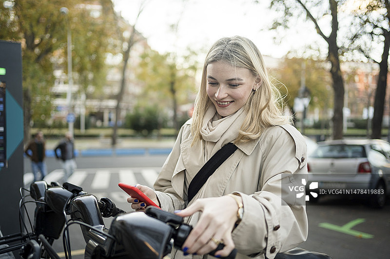 微笑的女人在停车场租电动自行车图片素材
