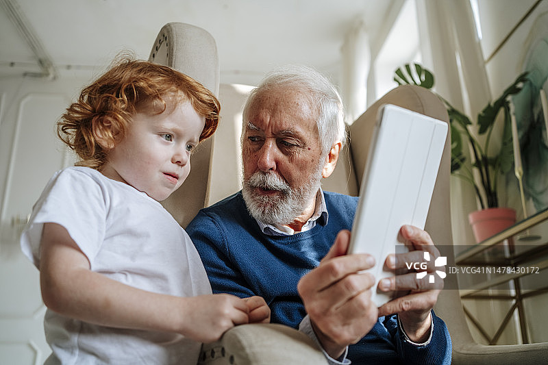 爷爷在家给孙子看平板电脑图片素材