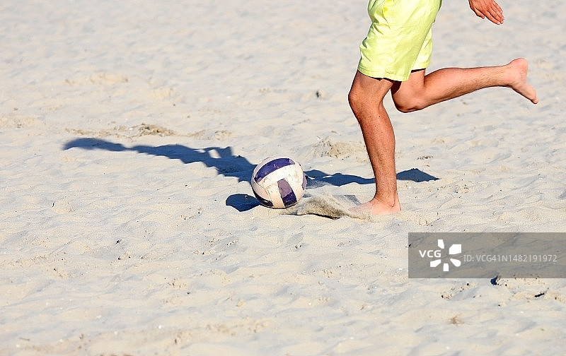 和朋友在沙滩上踢足球，度假。图片素材