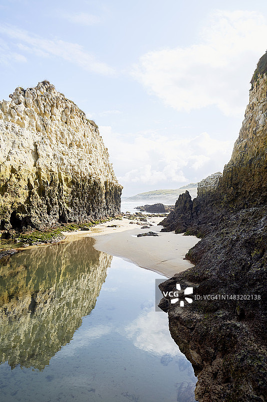 西班牙坎塔布里亚海岸落潮时风景如画的岩石，天空和岩石映照在海滩的水坑里图片素材
