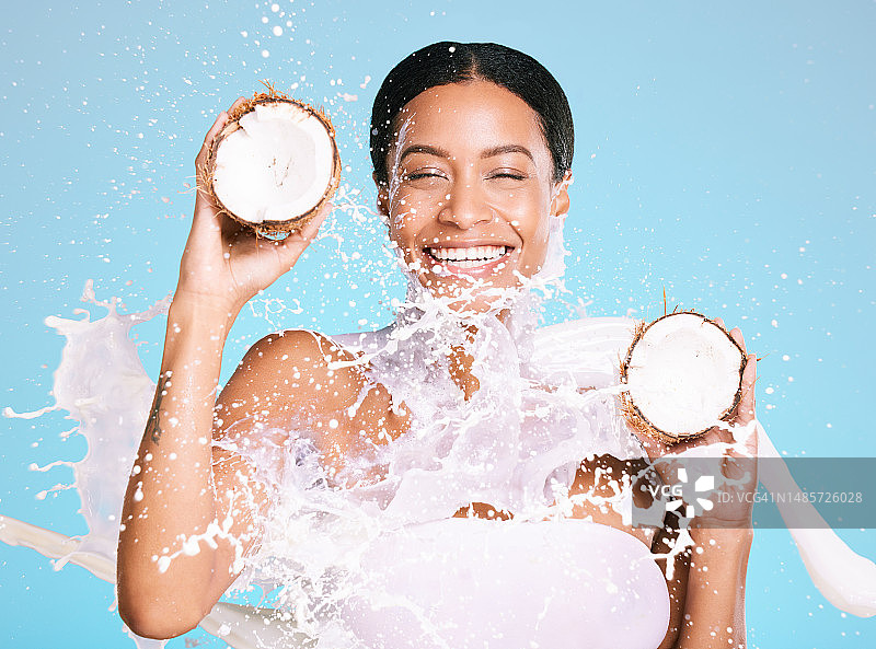 美容，护肤和女人用椰子健康皮肤和饮食在蓝色背景。快乐的审美模特的脸与牛奶飞溅和水果可持续的面部健康和保健图片素材