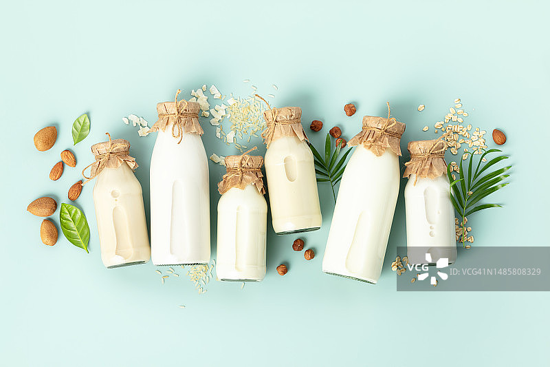 非乳制品工厂基于牛奶的瓶子和成分在绿松石背景替代无乳糖牛奶替代品，平坦，罗马尼亚图片素材