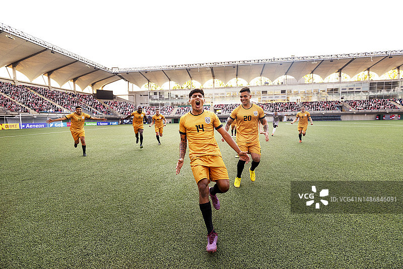 在一场国际比赛中，一名欣喜若狂的男足球运动员跑下体育场欢呼庆祝图片素材