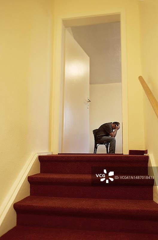 绝望的男人坐在门后楼梯的椅子上，60岁，抑郁，焦虑，绝望，担忧，奥地利上奥地利图片素材