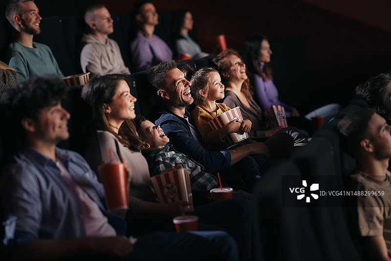欢乐的一家人在电影院看一部有趣的电影。图片素材