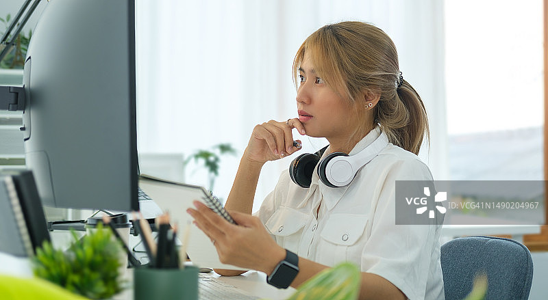 专注的年轻女企业家看着笔记本电脑屏幕，在她的工作场所处理文件。图片素材