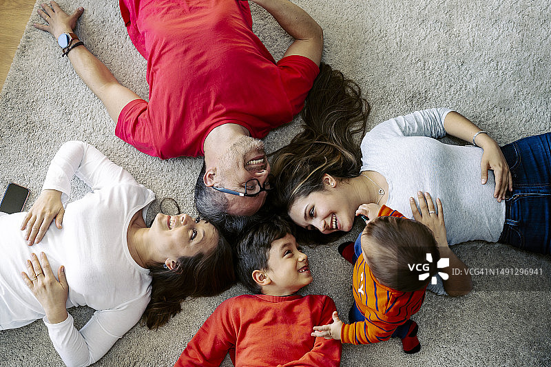 幸福的一家人躺在家里的地毯上图片素材
