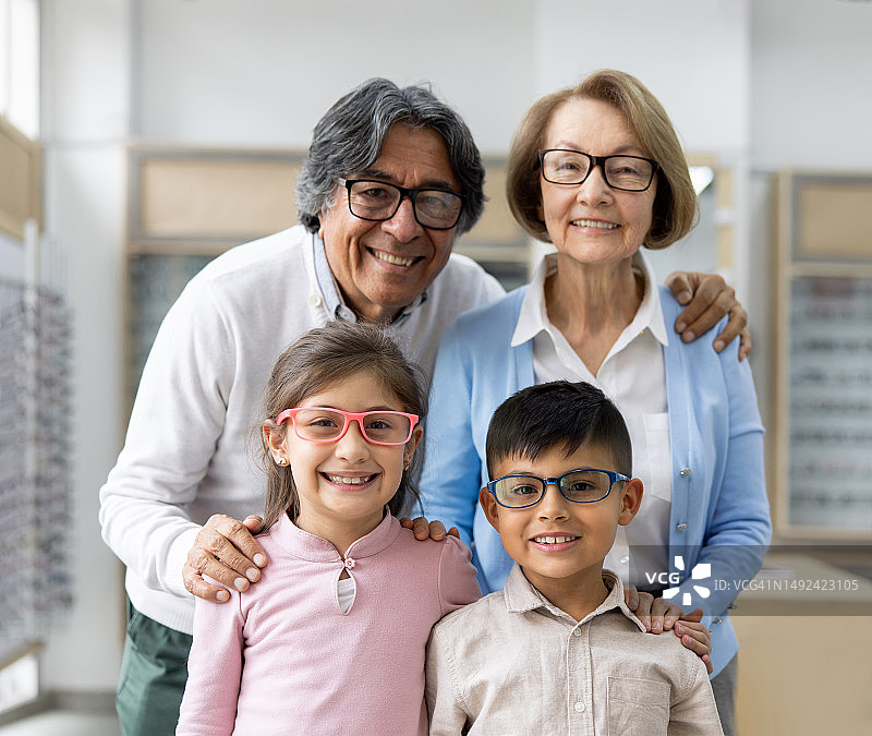 快乐的祖父母和他们的孙子戴着眼镜在眼镜店图片素材