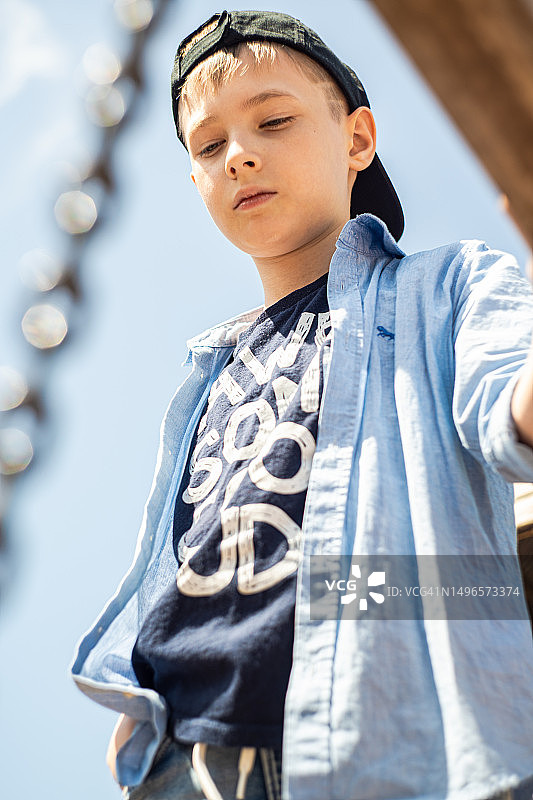 一个戴着棒球帽的小男孩在操场上的画像图片素材