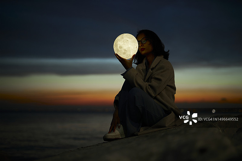 一位年轻的女士在户外玩月亮形的人造灯图片素材