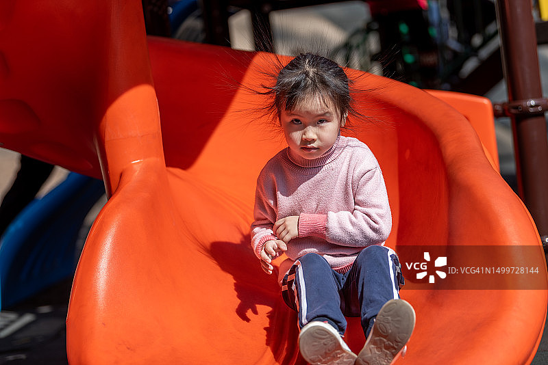 一个小女孩在游乐园玩滑梯图片素材