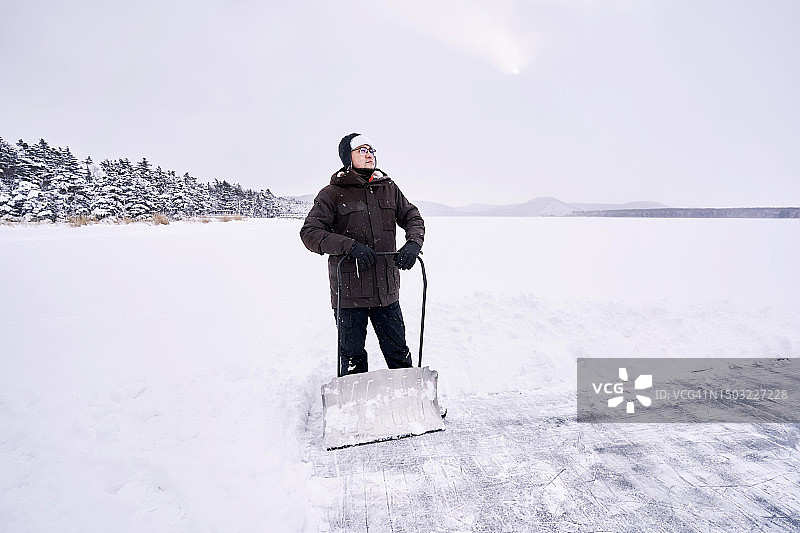 一名男子正在清理湖面上临时搭建的溜冰场。图片素材