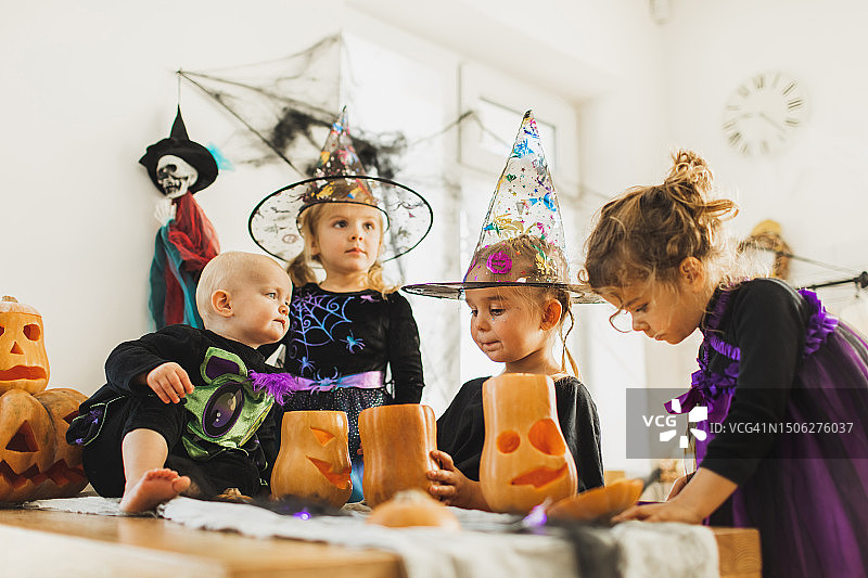 万圣节儿童派对。女婴制作传统的南瓜灯作为家庭装饰图片素材