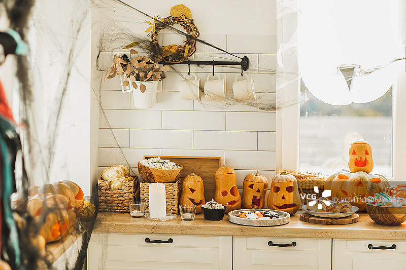 厨房里的万圣节装饰有蜘蛛网，蜡烛，可怕的南瓜灯。桌上的饼干图片素材