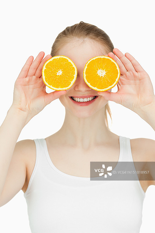 快乐的女人把橘子放在眼睛上图片素材