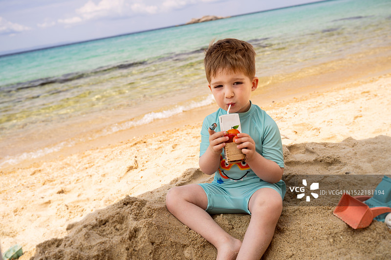 小男孩在海滩上喝果汁图片素材