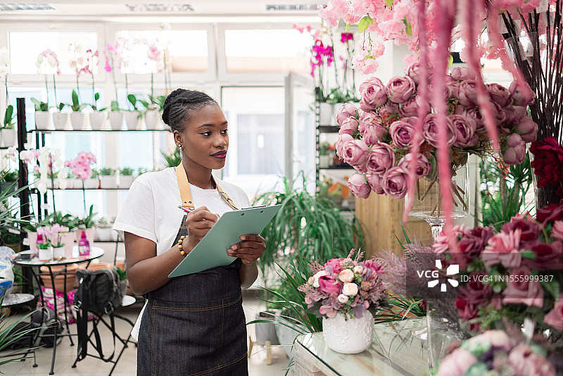 黑人女花店老板清点库存，对植物进行质量控制图片素材