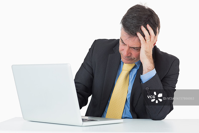 一个拿着笔记本电脑坐在办公桌前的麻烦男人图片素材