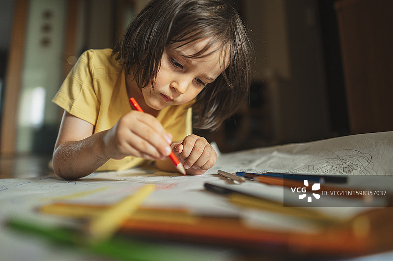 专心的男孩在家里用彩色铅笔画画图片素材