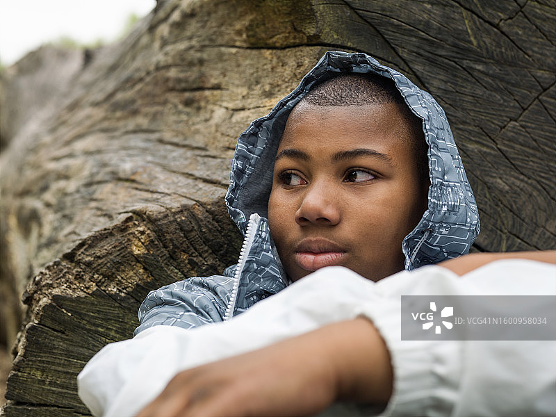 年轻的黑人男子坐在倒下的树下图片素材