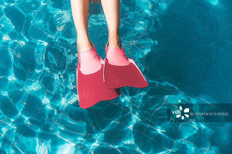 暑假季节的概念性形象。一个人在游泳池里游泳，穿着亮粉色的芭比娃娃芯浮潜鳍图片素材