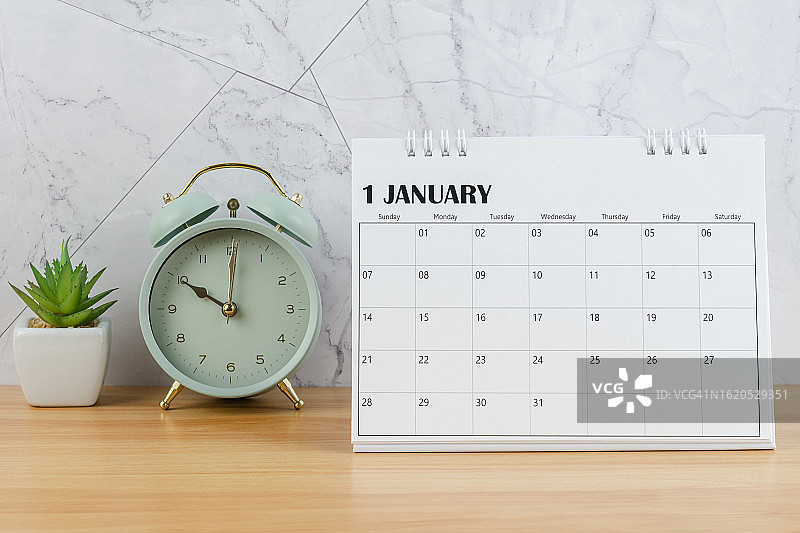 日历桌2024:1月是组织者计划和截止日期的月份，室内植物和闹钟以木桌为背景。图片素材
