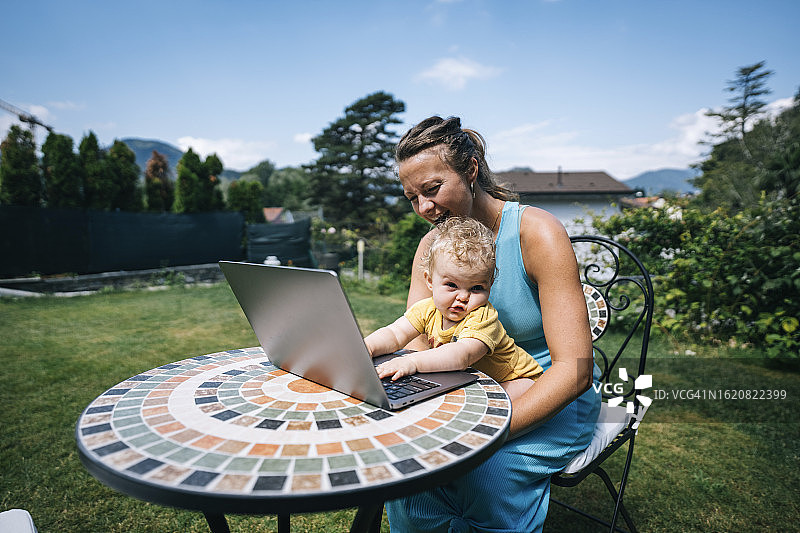 母亲和婴儿在户外用笔记本电脑工作图片素材
