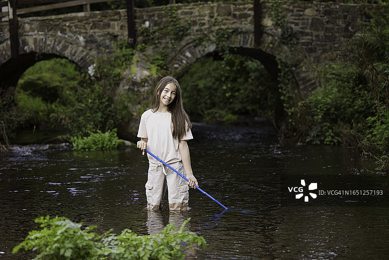 11岁的小女孩在小溪里拿着她的渔网图片素材