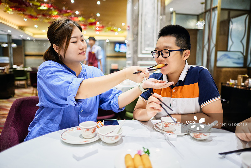 亚洲女人在咖啡馆喂他儿子图片素材